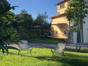 dos sillas sentadas en el césped frente a una casa en Podere La Cava en Chianciano Terme