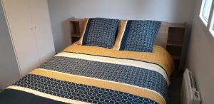 1 cama con almohadas azules y amarillas en una habitación en Jolie Maison neuve & WIFI Jardin Disneyland Paris 4 personnes, en Faremoutiers