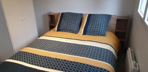 a bed with blue and yellow pillows in a room at Calme Studio & WIFI Jardin Disneyland Paris 4 personnes in Faremoutiers +18 photos