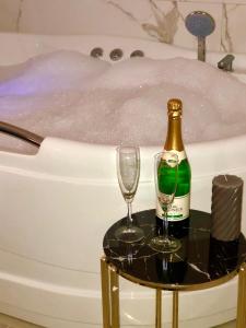 a bottle of champagne and two glasses in front of a bathtub at Guesthouse Dabić in Zlatibor