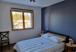 Schlafzimmer mit einem großen Bett und einem Fenster in der Unterkunft Chalet de charme avec terrasse, jardin et sauna extérieur in Chapelle-des-Bois