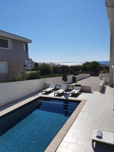 a swimming pool with chaises and chairs on a patio at Seastar Luxury apt with PRIVATE POOL and sea view in Novalja
