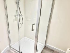 a shower with a glass door in a bathroom at Waterloo Townhouse Inverness in Inverness
