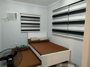 a small bedroom with a bed and two windows at Lucky Swiss Transient House Alaminos - Entire House near Hundred Islands in Bolo