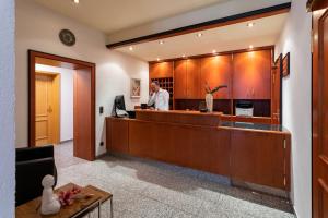 a man standing at a reception desk in a lobby at Hotel am Ludwigskanal in Wendelstein