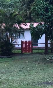 einen roten Zaun vor einem weißen Haus in der Unterkunft Vivenda dos Guaranys: casa + loft in Conservatória