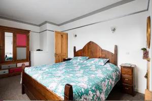 a bedroom with a large wooden bed and a dresser at Lovely Three Bedroomed House, Parking 2 Cars in London