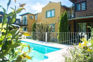 a villa with a swimming pool in front of a house at CABAÑAS del DIQUE TANDIL in Tandil