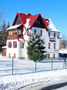 ein weißes Gebäude mit rotem Dach im Schnee in der Unterkunft Willa Velde in Karpacz