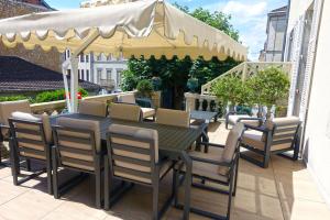 - une table et des chaises sous un parasol sur la terrasse dans l'établissement EXCEPTIONNEL PROPRIETE STANDING 90 m2 PARKING PRIVE BEL EXTERIEUR CENTRE VILLE CLIMATISE, à Périgueux