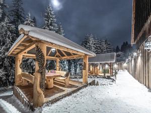 un cenador de madera en la nieve por la noche en Zagroda Krowiarki Chochołów en Chochołów