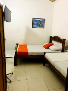 a room with two beds and a tv in it at Hostal La Española de Getsemani in Cartagena de Indias
