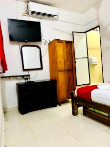 a bedroom with a bed and a tv and a mirror at Hostal La Española de Getsemani in Cartagena de Indias