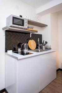 a white kitchen with a microwave and a sink at Ski Escape Apartment in Gudauri in Gudauri