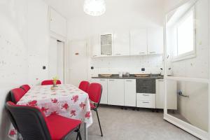 ローマにあるLabriola St Peter's House- Free parkingの白いキッチン(テーブル、赤い椅子付)