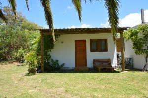 una pequeña casa blanca con un banco en el patio en Buenavida, en La Pedrera