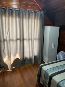 ein Schlafzimmer mit einem Bett und einem Vorhang in der Unterkunft Chalés Vô João in Penha