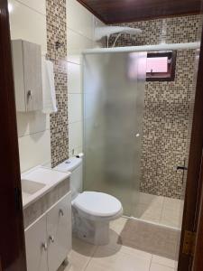 a bathroom with a toilet and a glass shower at Chalés Vô João in Penha