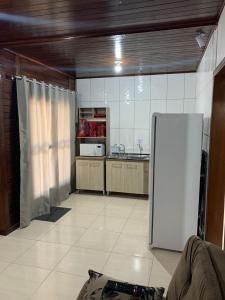 a kitchen with a white refrigerator in a room at Chalés Vô João in Penha