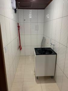 ein kleines, weiß gefliestes Zimmer mit einem Waschbecken. in der Unterkunft Chalés Vô João in Penha