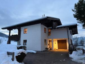 een groot wit huis in de sneeuw bij Haus Schreder in Saalfelden am Steinernen Meer