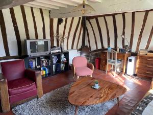 ein Wohnzimmer mit einem Sofa und einem Tisch in der Unterkunft Belle Longère normande, cheminée et jardin arboré in Canville-les-Deux-Églises