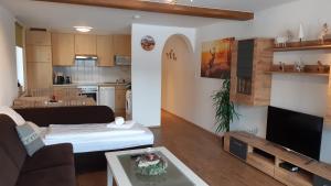 un salon avec un canapé et une télévision et une cuisine dans l'établissement Apartment Romy, à Kaprun