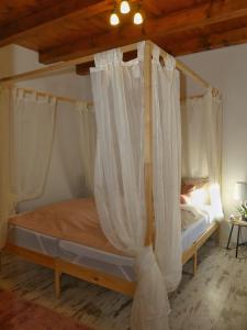 sypialnia z łóżkiem z baldachimem i białymi zasłonami w obiekcie Csücsök vendégház w Egerze