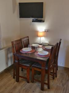 a wooden table with four chairs and a television at Csücsök vendégház in Eger