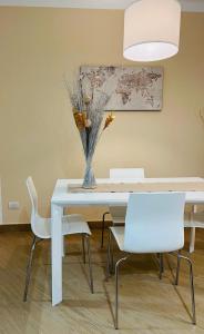 uma mesa de jantar com cadeiras brancas e um vaso com flores em ComeCasa modern apartment in historical centre em Asti