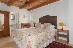 Schlafzimmer mit einem großen Bett mit einem Kopfteil aus Holz in der Unterkunft Hotel Roosje van de Kaap in Swellendam