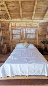 ein großes Bett in einem Holzzimmer mit zwei Fenstern in der Unterkunft Pachingo Tatacoa Desert in La Victoria