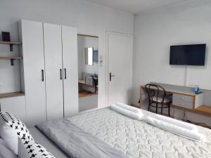 a white bedroom with a bed and a desk at The House Apartments & Guest Rooms in Ohrid