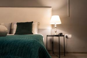 a bedroom with a bed with a green blanket and a lamp at Sliema Marina Hotel in Sliema