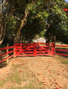 una valla roja frente a un campo con árboles en Vivenda dos Guaranys: casa + loft en Conservatória