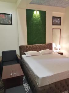 1 dormitorio con cama y pared verde en Hotel Hoque Tower International, en Chittagong