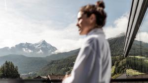 Eine Frau, die aus einem Fenster auf einen Berg schaut. in der Unterkunft die berge lifestyle-hotel sölden in Sölden