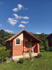 una pequeña casa de ladrillo con una ventana en un campo en Recanto da Serra, en São Thomé das Letras