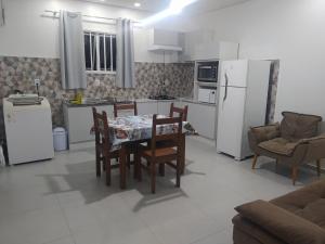 cocina con mesa, sillas y electrodomésticos blancos en Trentino 66 - Hospedagem em Ijuí, casa agradável com estacionamento en Ijuí