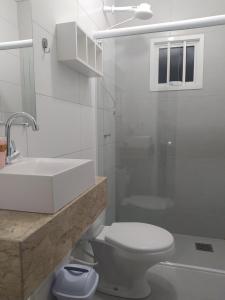 La salle de bains blanche est pourvue de toilettes et d'un lavabo. dans l'établissement Trentino 66 - Hospedagem em Ijuí, casa agradável com estacionamento, à Ijuí