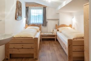 two beds in a room with a sink at Apartments UDERA in Selva di Val Gardena