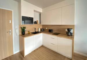 a kitchen with white cabinets and a wooden floor at Urokliwy apartament HAVEN nad morzem+free parking in Kołobrzeg