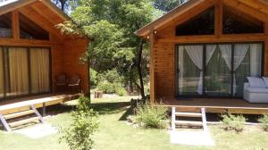 Cabaña de madera con porche y sillas en el patio en Cabañas El Druida en Villa General Belgrano