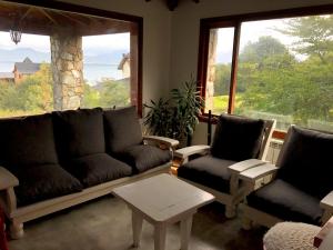 a living room with a couch and two chairs and a window at Villa de los Ñires in Ushuaia
