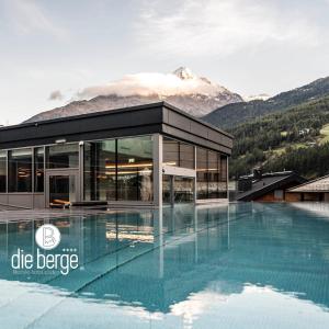 a building with a pool in front of a mountain at die berge lifestyle-hotel sölden in Sölden