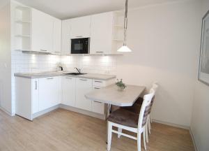 a kitchen with white cabinets and a table and chairs at STRANDIDYLL, 12 - Typ A2S in Grömitz