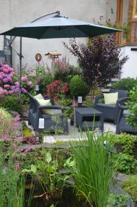 un patio con sillas y una sombrilla en un jardín en Gästehaus Praliné en Bremm