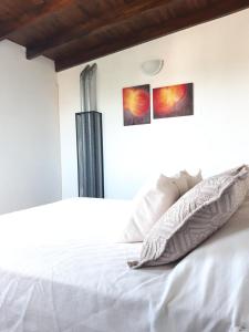 Dúplex La Falda في لا فالدا: غرفة نوم بسرير ابيض مع وجود صورتين على الحائط