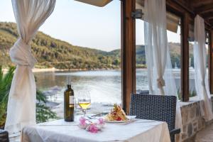 a table with a glass of wine and a plate of food at Blue Green Bay in Panormos Skopelos