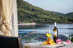 a table with a glass of white wine and pasta at Blue Green Bay in Panormos Skopelos